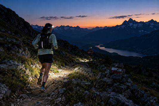 Twee trailrunners met hoofdlampen op een bergpad in de schemering